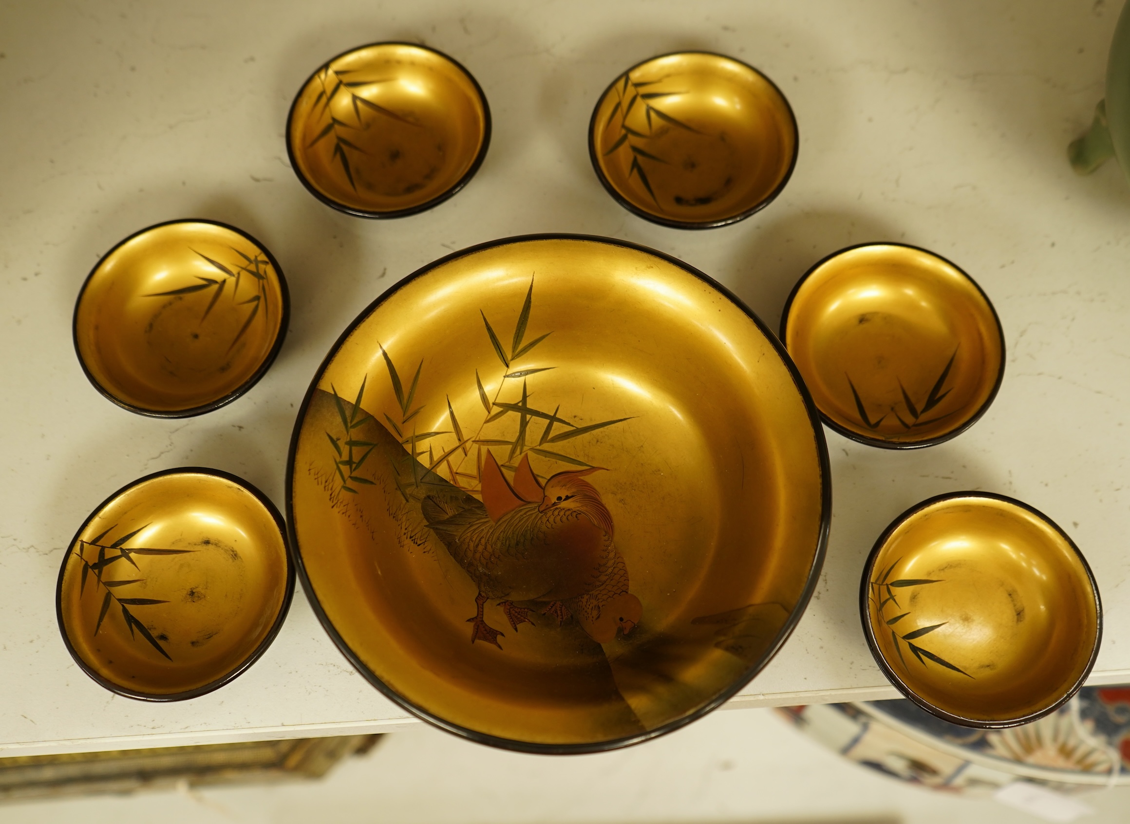 A Japanese lacquer bowl with gilt interior decorated with birds and six small dishes, largest 15cm in diameter